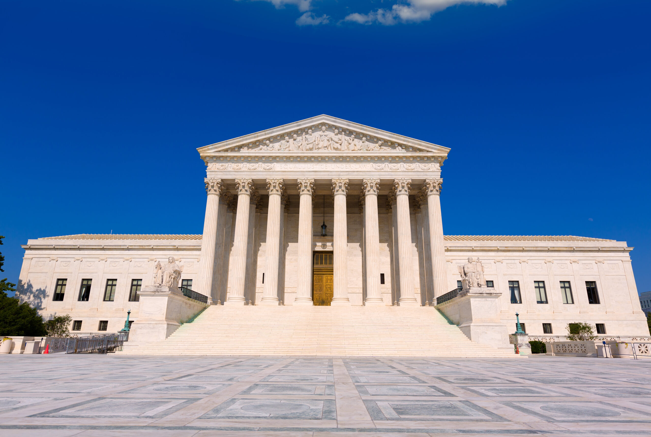 White neoclassical temple with tall fluted columns and a large set of steps against a clear blue sky, conveying a sense of law and justice.