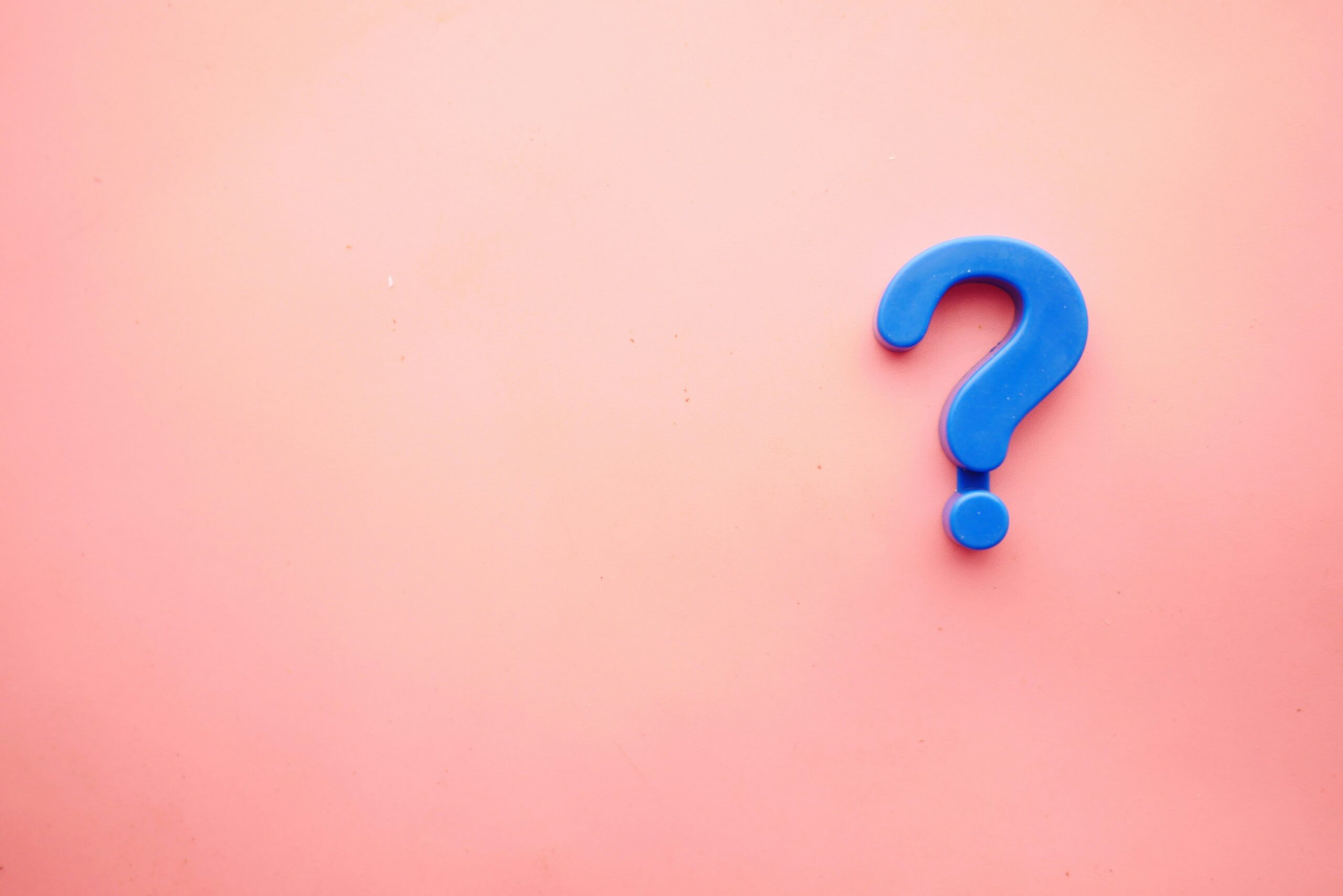 Blue question-mark shaped object in the bottom-right corner against a pink background.